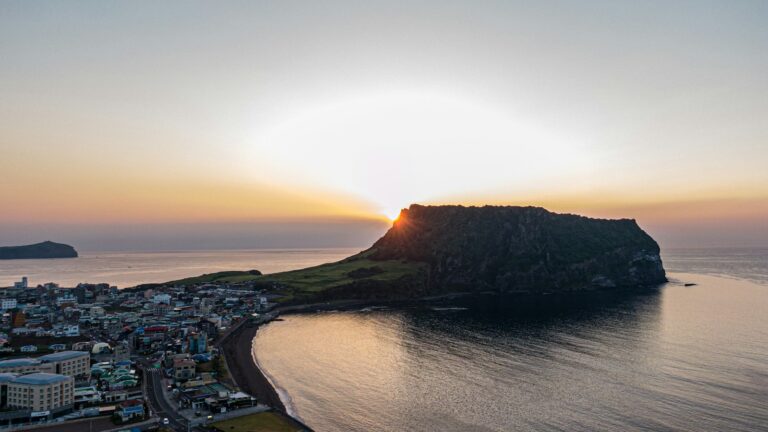 Seongsan Ilchulbong Sunrise beside Seongsan Ilchulbong and the coastal village on Jeju Island.